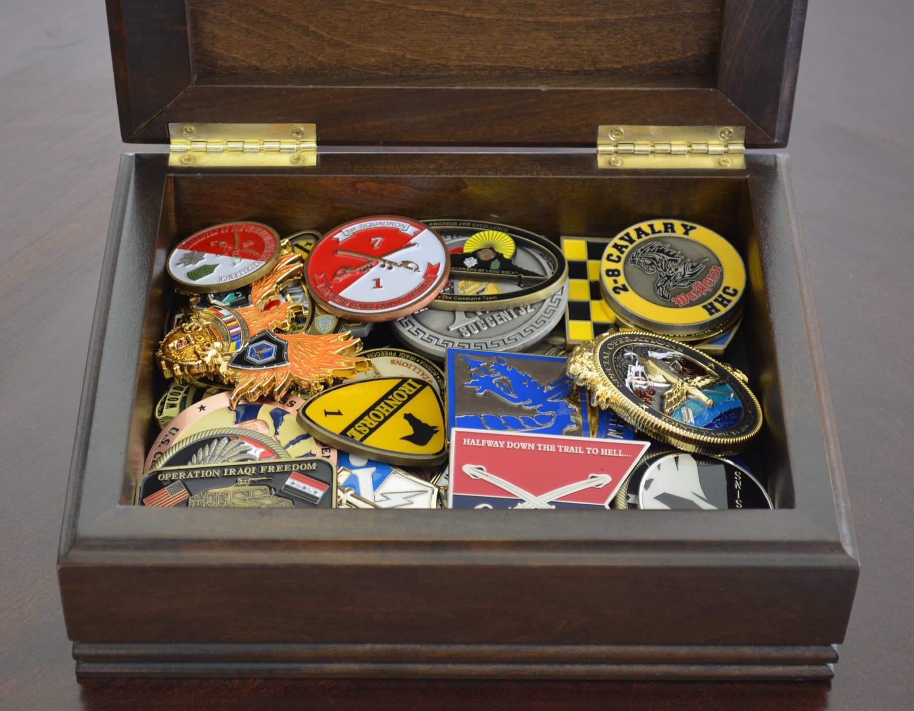 Open wooden box filled with military challenge coins